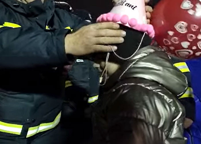 An officer gives the little girl a party hat as she receives more gifts.