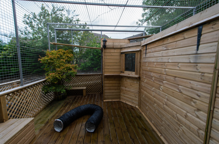 Couple standing near a tall cat pen, facing angry neighbours