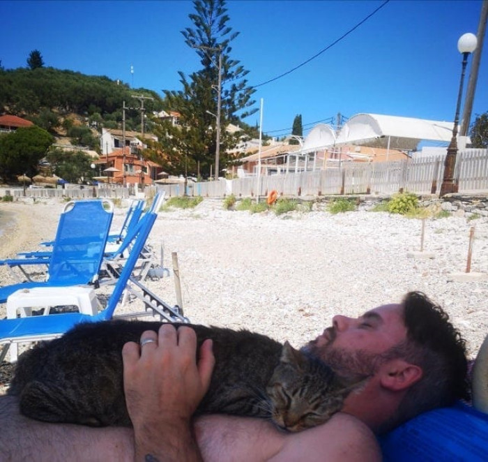 The local beach cat went basking with him under the Corfu sun.