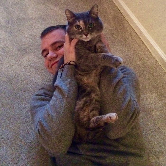 Sam and Ruby cuddle together, showing a close cat-human bond.