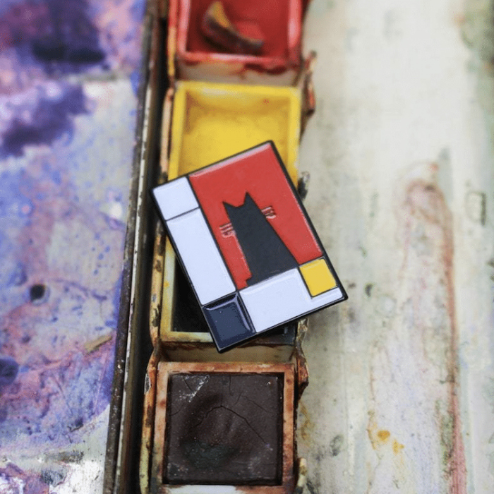 Piet Mondrian reimagined as Meowdrian, cat-themed enamel pin with geometric stripes.