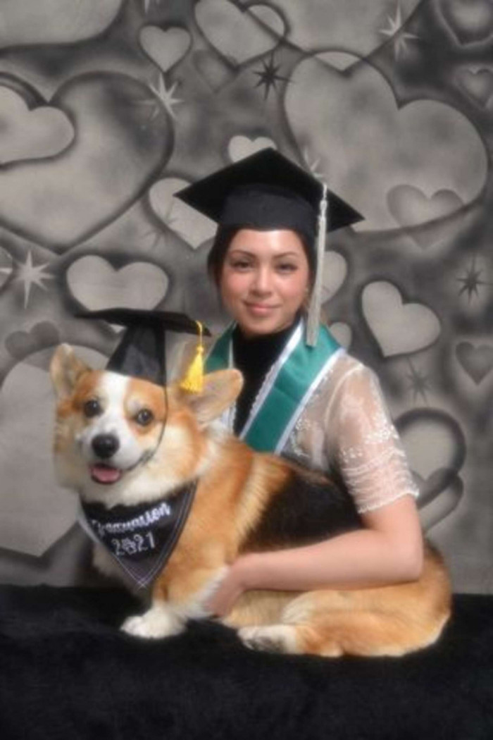 Cap and gown photo moment, student and dog looking at camera