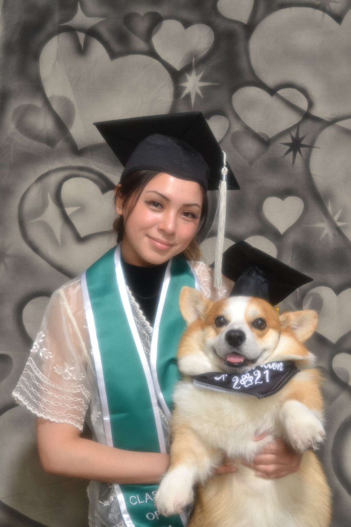 Close-up of the graduate holding a leash, dog beside her