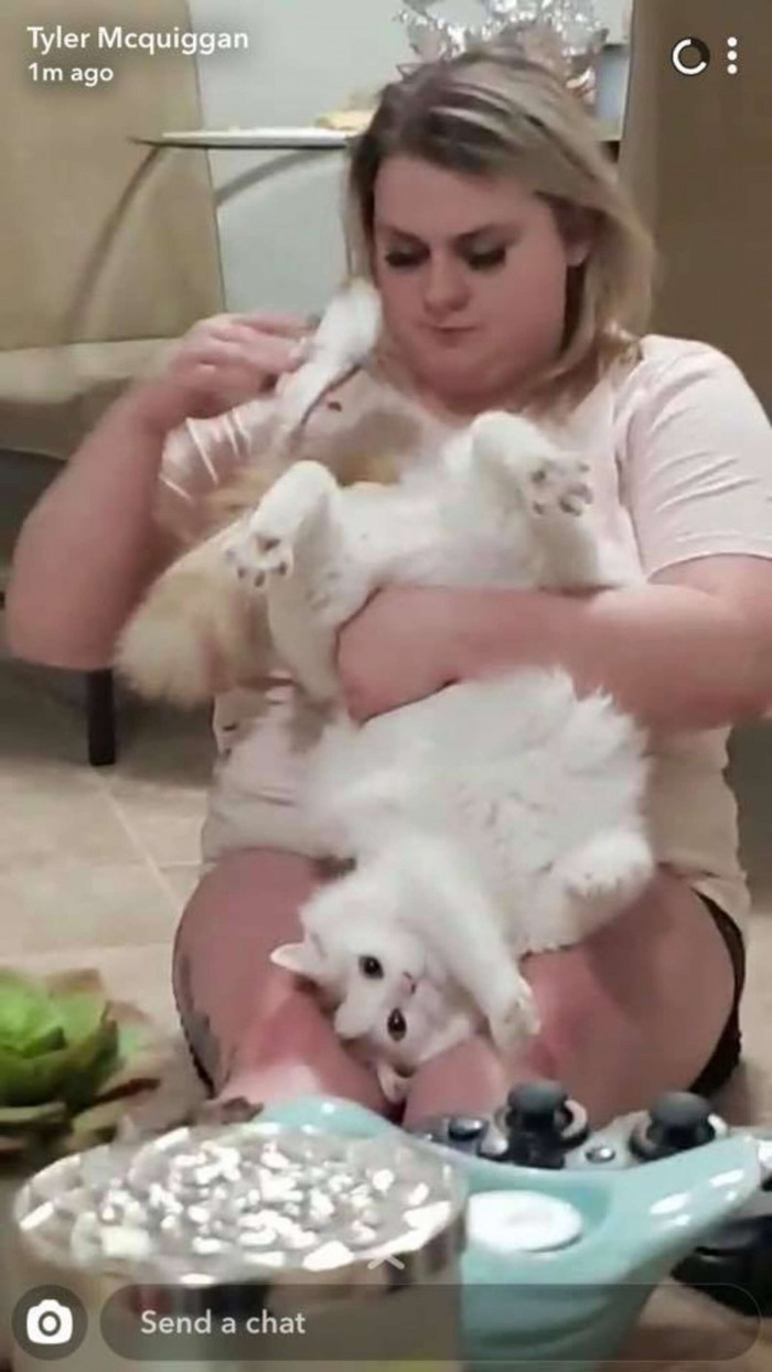 Woman gently holds her cat while performing an unusual grooming routine.