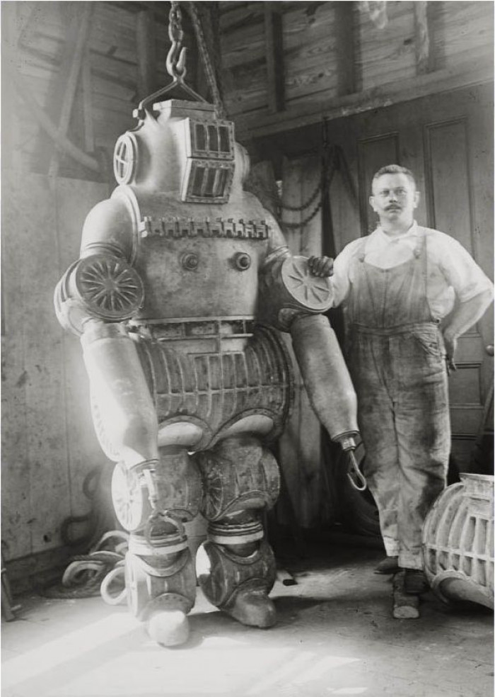 Chester E. Macduffee standing next to his invention, a 250-kilo diving suit