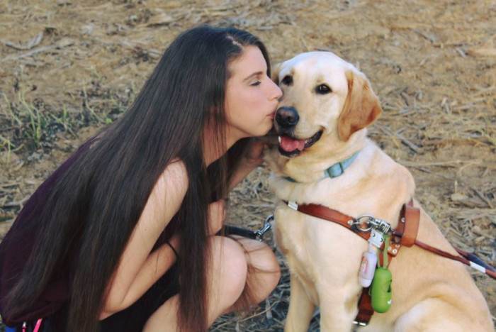 Thai, a guide dog, sits beside Danielle at a mall visit.