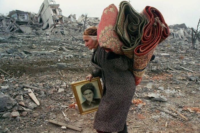 4. The old woman who was given 5 minutes to pack and leave before the Russian army destroyed her home leaves with rugs and a photo of her husband.