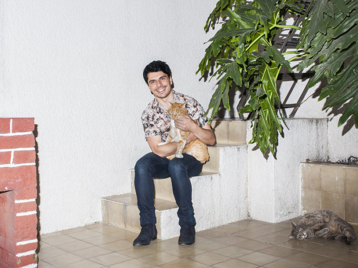 Man posing at home with cat, photographer captures feline companion