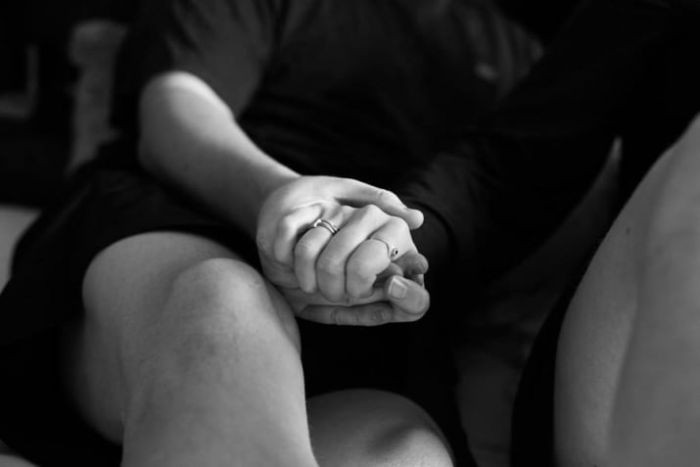 Couple poses for kitty maternity photoshoot, with a baby kitten prop.