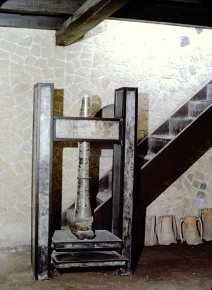 23. A 1961 photo depicts a unique screw press found in Herculaneum's Workshop of Lanarius, the only item discovered there alongside the Bourbon Tunnels. No other similar presses have been found.