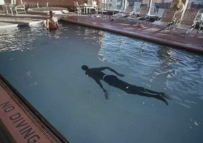 7’7″ NBA legend Manute Bol swimming in a normal pool.